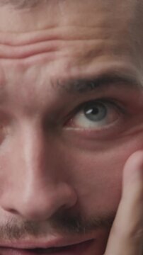 Extreme close-up of a young man looking anxious, scared and panicked, touching his face and covering his ears 