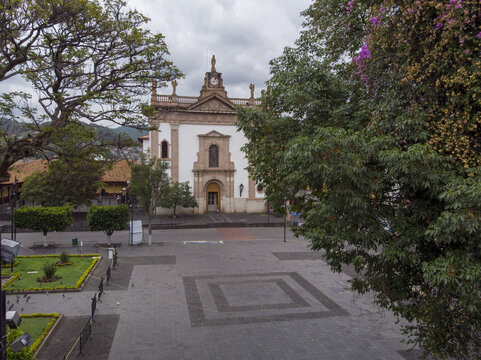Aerial view of the Parroquia de San Francisco in the historic downtown plaza surrounded by lush trees and stone walkways in Uruapan, Michoacan, Mexico.
