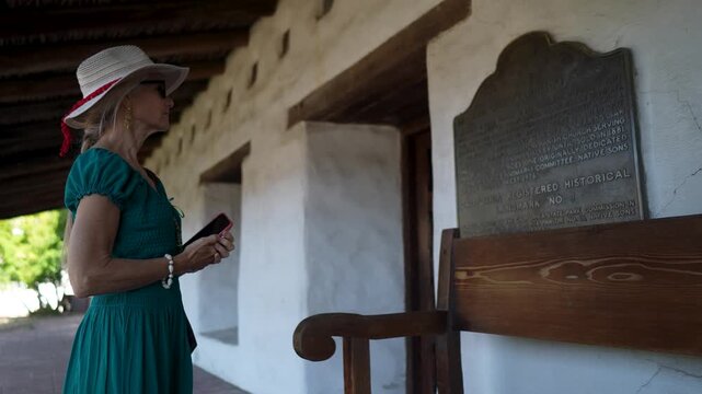 Senior woman smiles and explores the Mission church San Francisco Solano de Sonoma, learning about its history in California.
