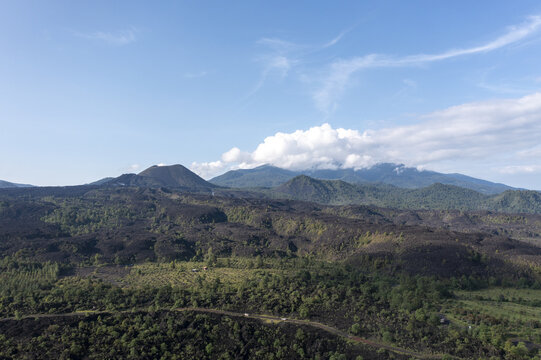 Aerial view of Volcan Paricutin showing the vast volcanic lava fields surrounded by lush green forests and mountains under a clear blue sky in Uruapan, Michoacan, Mexico.