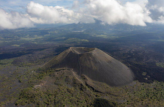 Aerial view of the volcanic cone of Paricutin surrounded by solidified lava fields and sparse vegetation under a cloudy sky in Uruapan, Michoacan, Mexico.