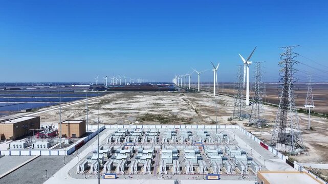 Wind farm substation with rows of wind turbines under clear blue sky