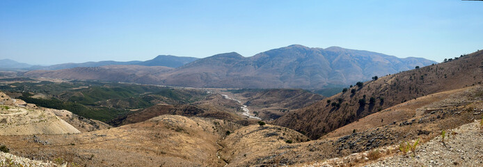 Panoramic view of arid canyon with dry riverbed winding between rocky mountain hills in Delvine region Albania © Катерина Котелевич