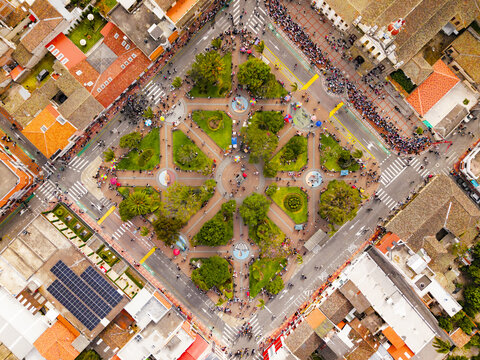 Aerial view of the central park with geometric pathways, lush green trees, and surrounding historic buildings in Ibarra, Imbabura, Ecuador.