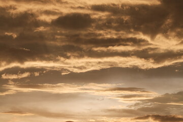 Fototapeta premium Dramatic clouds in the sky tinted with golden sunset colors after a heavy afternoon rainstorm