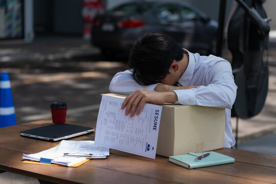 Frustrated man suffering from headache and job loss crisis looking at resume.
