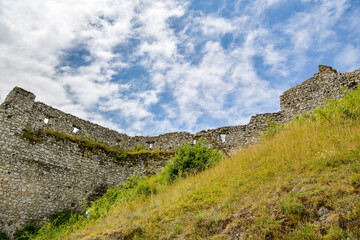 Ruined limestone castle walls under summer clouds © Michal