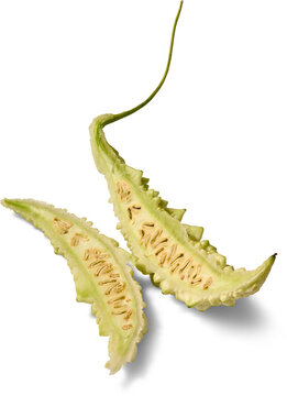 sliced bitter melon isolated white background, green bumpy skin and exposed seeds inside fresh vegetable, cut in half