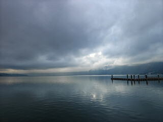 Fototapeta premium Moody Overcast View of Lake Batur with Wooden Pier and Misty Mountains in Bali