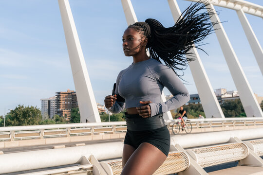 Determined athlete jogging on bridge on summer day 