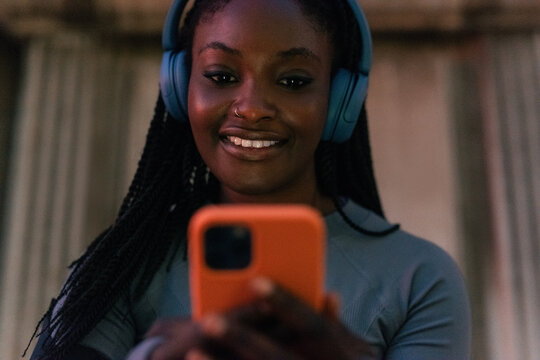 Woman is looking at screen of her smartphone and listening music 