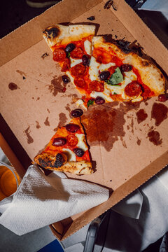 Remaining slices of pizza inside an open cardboard box