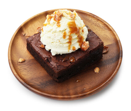 Delicious brownie with vanilla ice cream, caramel sauce and nuts isolated on white