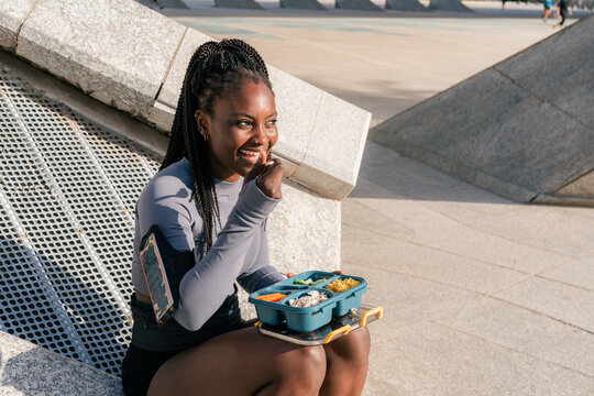 Woman Enjoys Lunch Outdoors While Sitting on a Stone Structure
