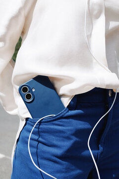 Smartphone and earphones in pocket with white shirt