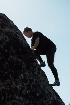 Woman bouldering on rock showcasing strength and determination