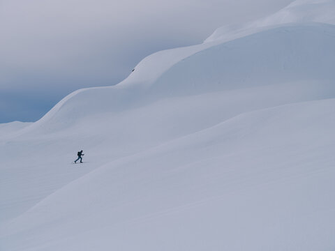 Distant Skier Traversing Vast Winter Mountain Landscape