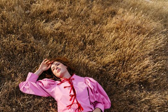 Woman in pink dress relaxing in a dry field