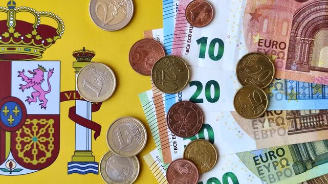 Spain, Spanish euro cash and cent coins against the background of the flag. Euro cash