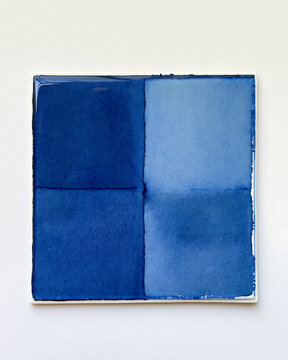 Square glass tile with four quadrants of blue watercolor pigment on