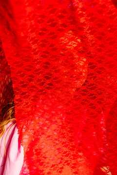 Woman behind red lace veil outdoors