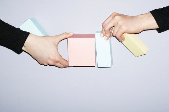 Hand holding pastel coloured mockup packages with empty space 