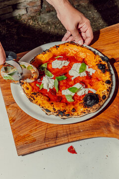Chef slicing a fresh homemade pizza with a cutter