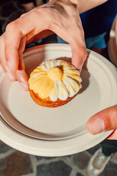 Hands holding a gourmet lemon meringue tartlet on a plate