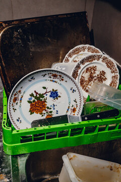 Dirty dishes and plates stacked in a green plastic crate for washing