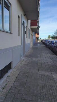 Daytime handheld first-person video walking along traditional montevideo urban street with cars parked at border