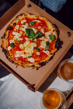 le
Artisanal pizza in a delivery box served with glasses of beer