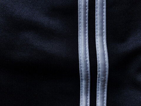 Closeup of black athletic fabric texture with double white stripes