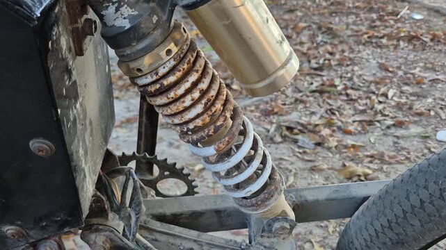 Close up of rusty rear shock absorber on old custom motorcycle outdoors
