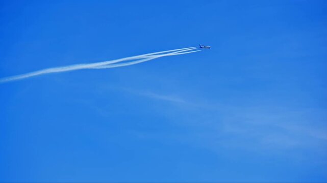 In the bright blue sky, a passenger plane was flying. The exhaust fumes from its engines released steam, creating long, white streaks.