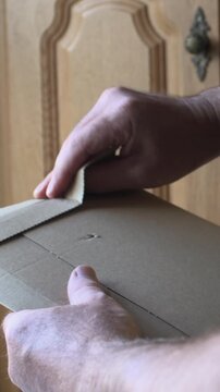 Man opening light carboard envelope parcel close up unboxing