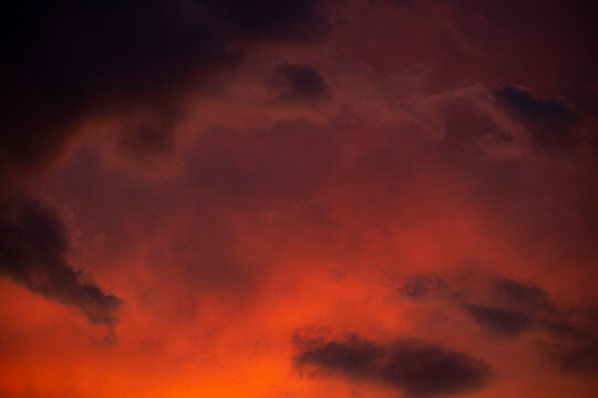 Dark red moody clouds at ominous sunset. Hidden danger in volcanic natural power.