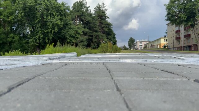 Gray concrete paving slabs stacked in rows wrapped in plastic film outdoors. Street repair materials, urban construction, building supply