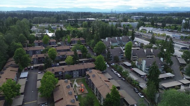 Shingled residential rooftops border Pete von Reichbauer Way S, as complex courtyards blend with dense timber stands, showcasing Pacific Northwest suburban housing structures in Federal Way, WA