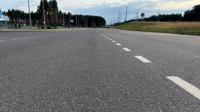 Empty asphalt road with white dashed markings running through a forest area. Quiet countryside street, open way, travel background