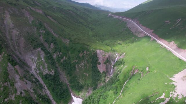 Epic cinematic drone flight above majestic green mountain valley with glaciers, winding serpentine road and lush Caucasus peaks in Svaneti, Georgia. for travel, meditation, wellness and nature project