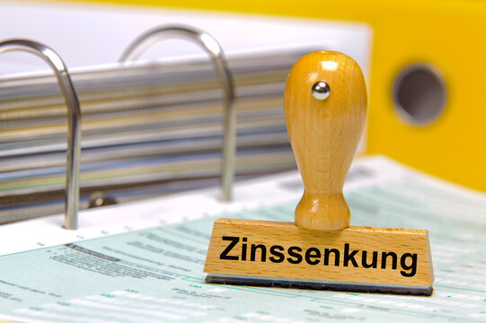 Ein Holzstempel ist bedruckt mit der Aufschrift: Zinssenkung