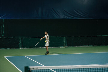 Fototapeta premium Young Asian Male Tennis Player Preparing to Serve on Indoor Blue Hard Court