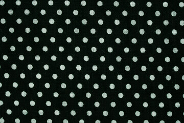 Black textile material presenting a repeating white polka dot pattern for a background © Floren Horcajo