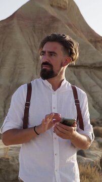 Caucasian man using cellphone looking for a direction in a desert. Copy space vertical footage.