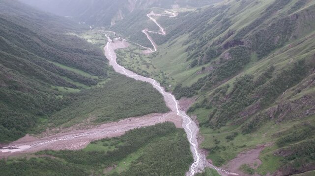 Epic cinematic drone flight above majestic green mountain valley with glaciers winding serpentine road and lush Caucasus peaks in Svaneti Georgia. for travel, meditation, wellness and nature projects