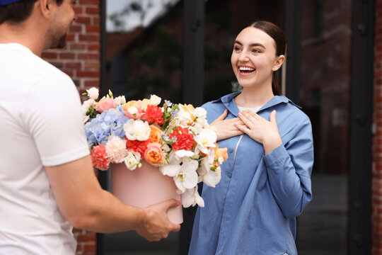 Courier giving beautiful bouquet of flowers to woman outdoors, closeup