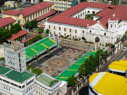 Aerial view of the historic Basilica del Santo Nino with its red roof and courtyard, surrounded by urban buildings and green structures in Cebu City, Central Visayas, Philippines.