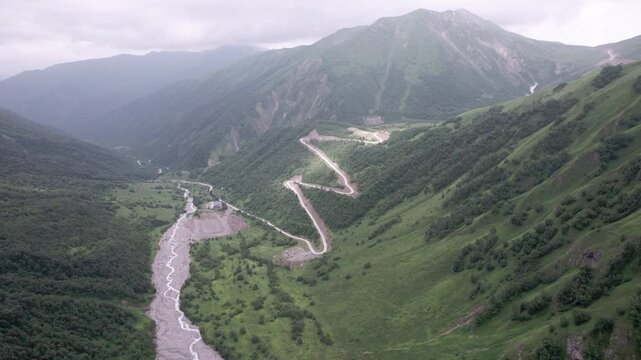 Epic cinematic drone flight above majestic green mountain valley with glaciers, winding serpentine road and lush Caucasus peaks in Svaneti, Georgia. for travel, meditation, wellness and nature project