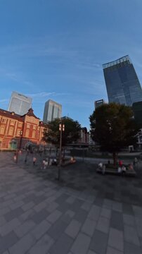 TOKYO, JAPAN -JUL 2026 : Aerial time lapse shot of Tokyo station and Kokyo Gaien National Garden (Imperial Palace Outer Garden) in sunset. Japanese urban city and business concept vertical video.