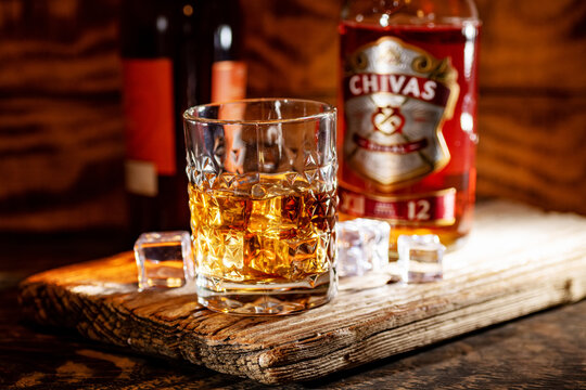 Chivas Regal 12 whisky tumbler stands before branded bottle and presentation box.